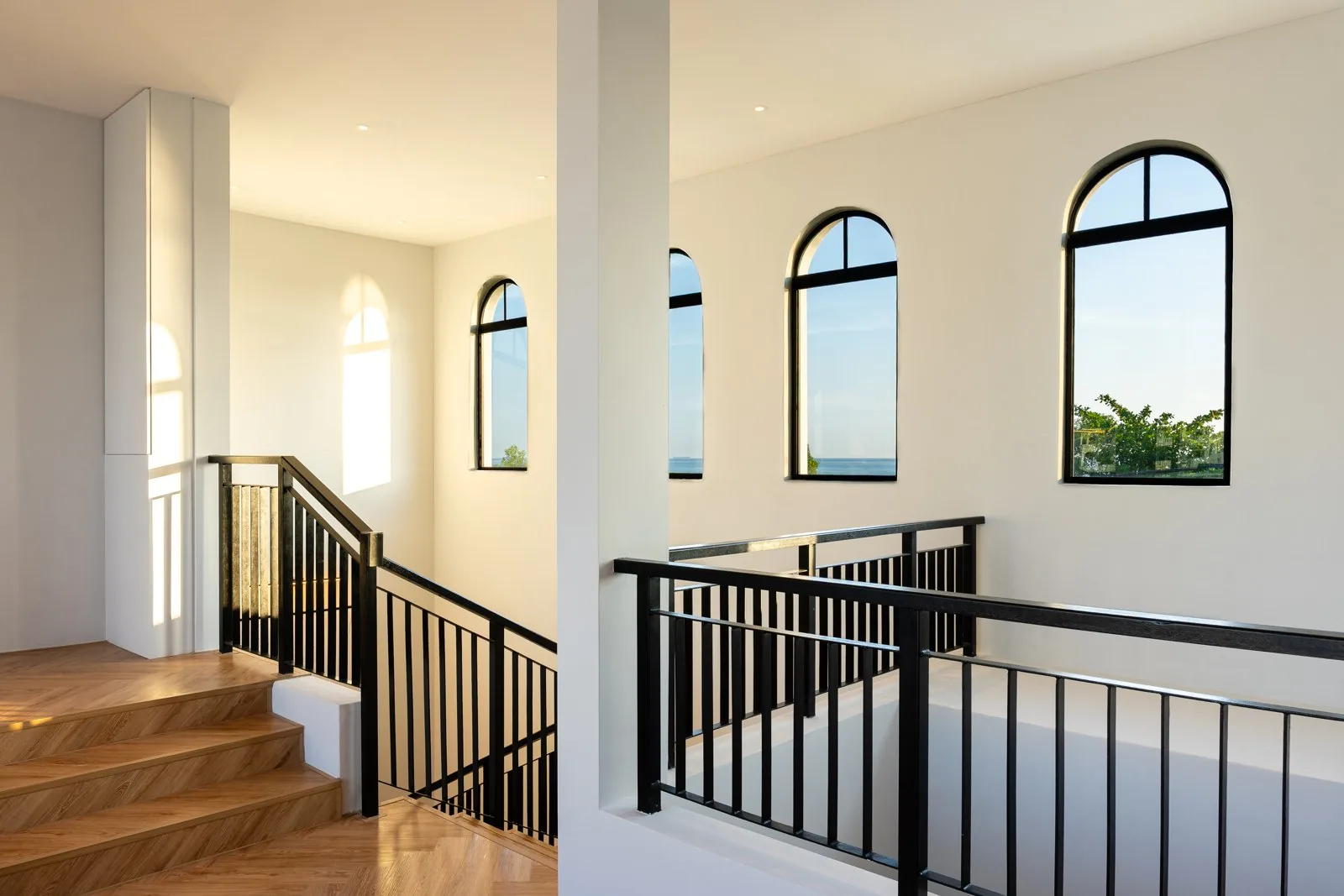Staircase with timber treads and a black metal balustrade rising to a landing in Quayside Villa, Port Dickson