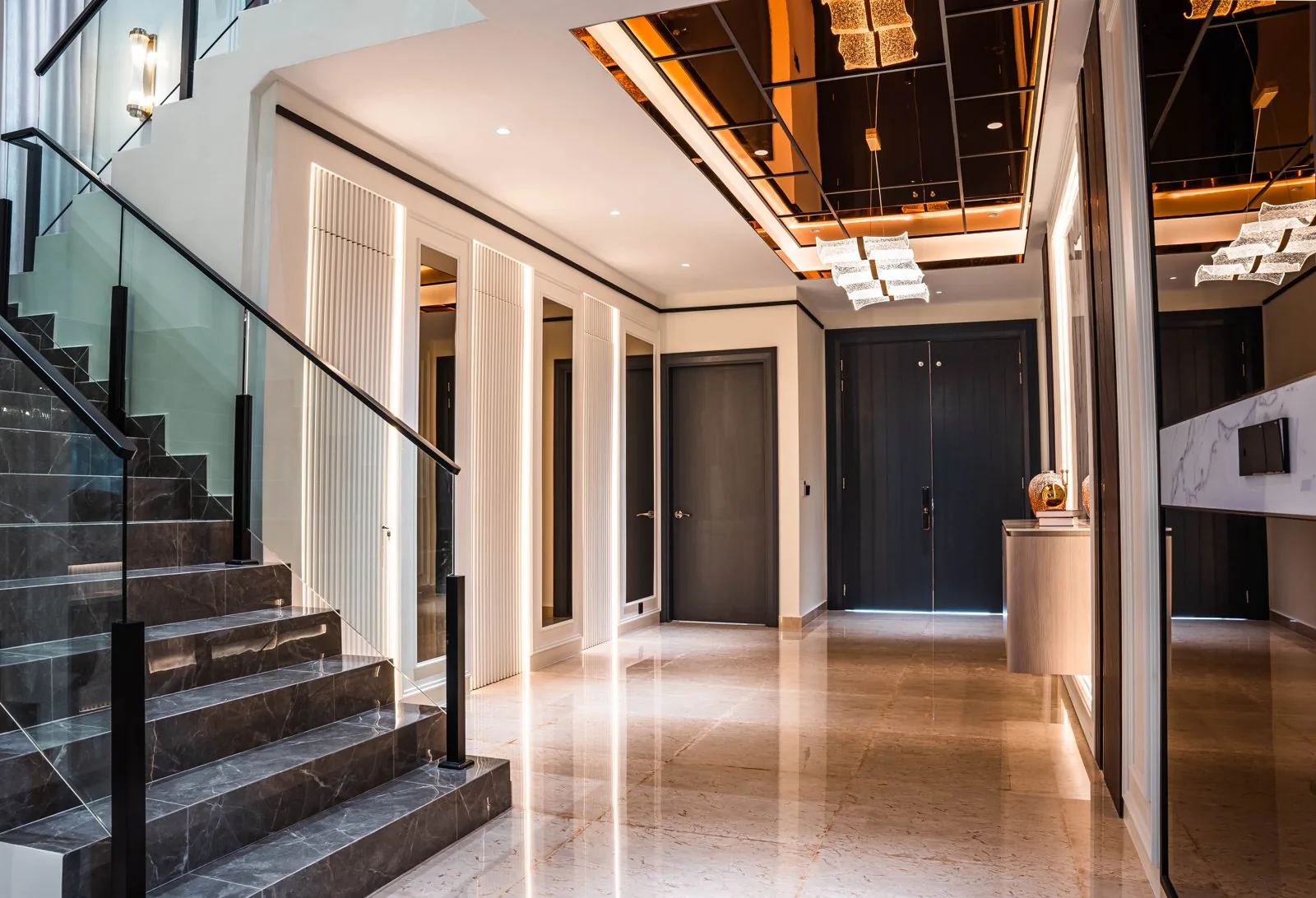 Stone staircase with a glass balustrade under a bronze mirror coffered ceiling at Setia Marina One, Cyberjaya