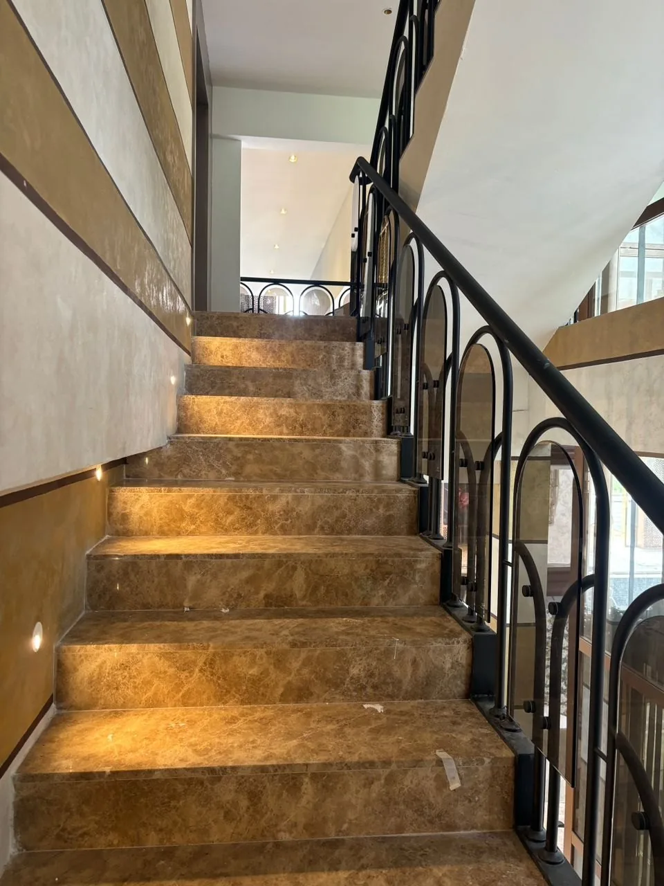 Stone stair treads with low step lights and a black metal balustrade at The Peak, Ampang