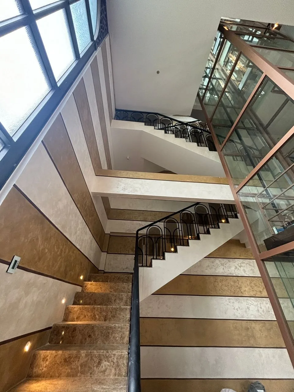 U shaped staircase wrapping around a glass lift with step lights at The Peak, Ampang