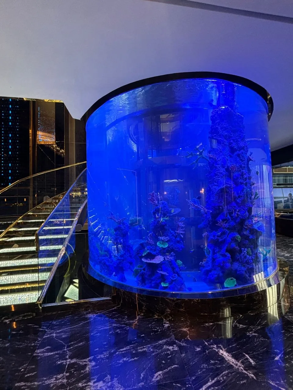 Cylindrical aquarium beside the lit staircase at The Peak, Ampang