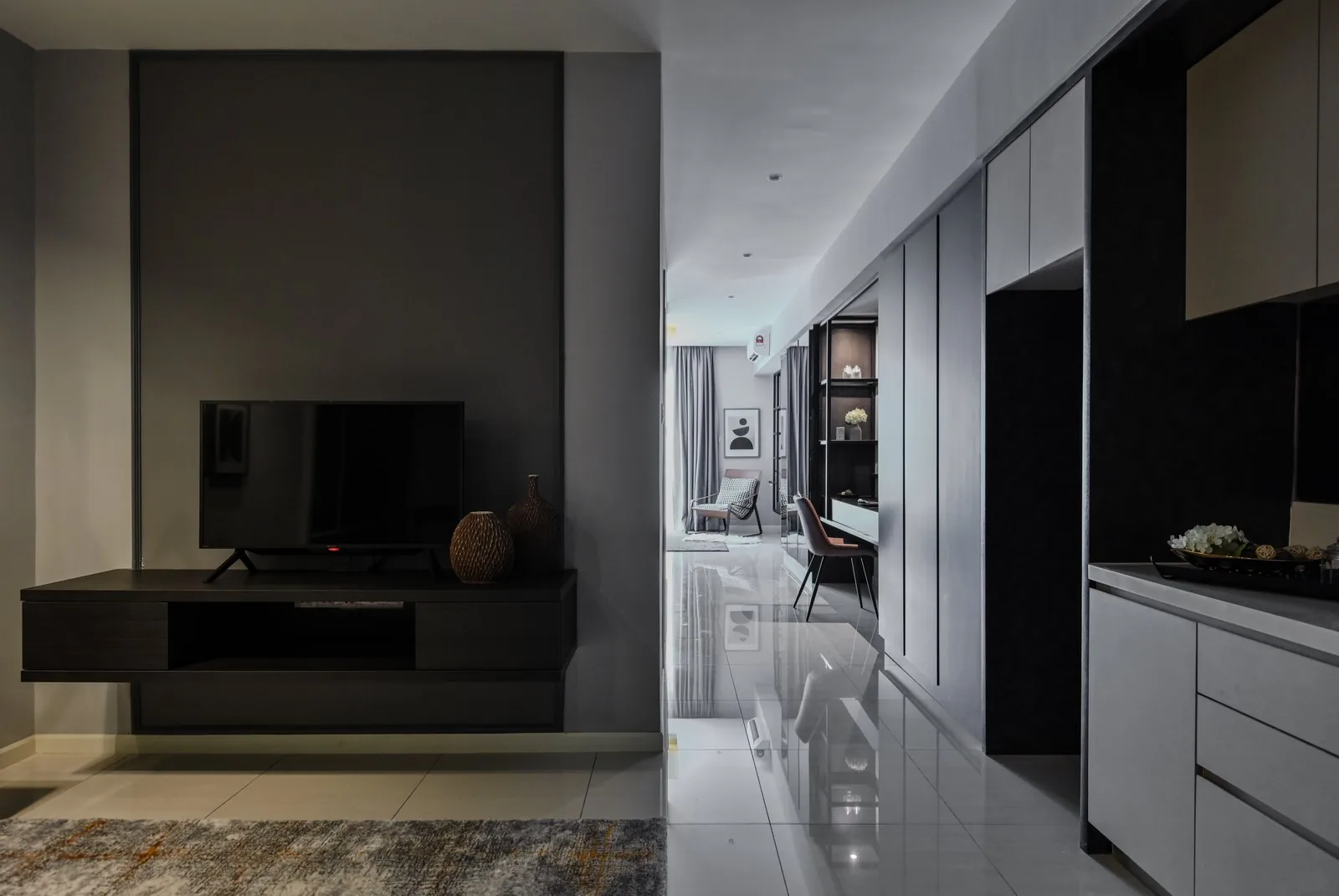 Dark floating TV console under a grey wall panel in the Dorsett Hartamas show unit