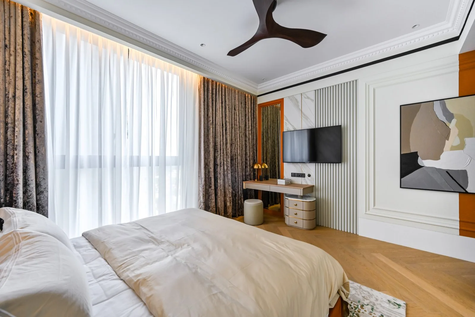 Bedroom with a wall mounted TV and floating desk against a fluted panel at Aira Residence