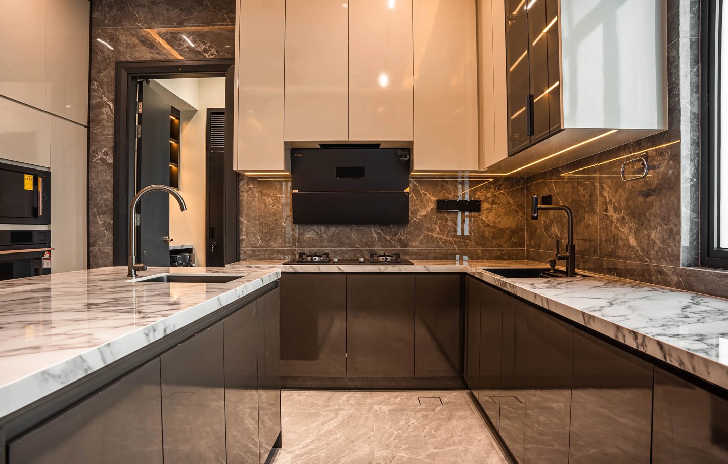 U-shaped kitchen design with marble countertops, marble backsplash and a concealed extractor hood at Setia Marina One, Cyberjaya, by Blaine Robert Design