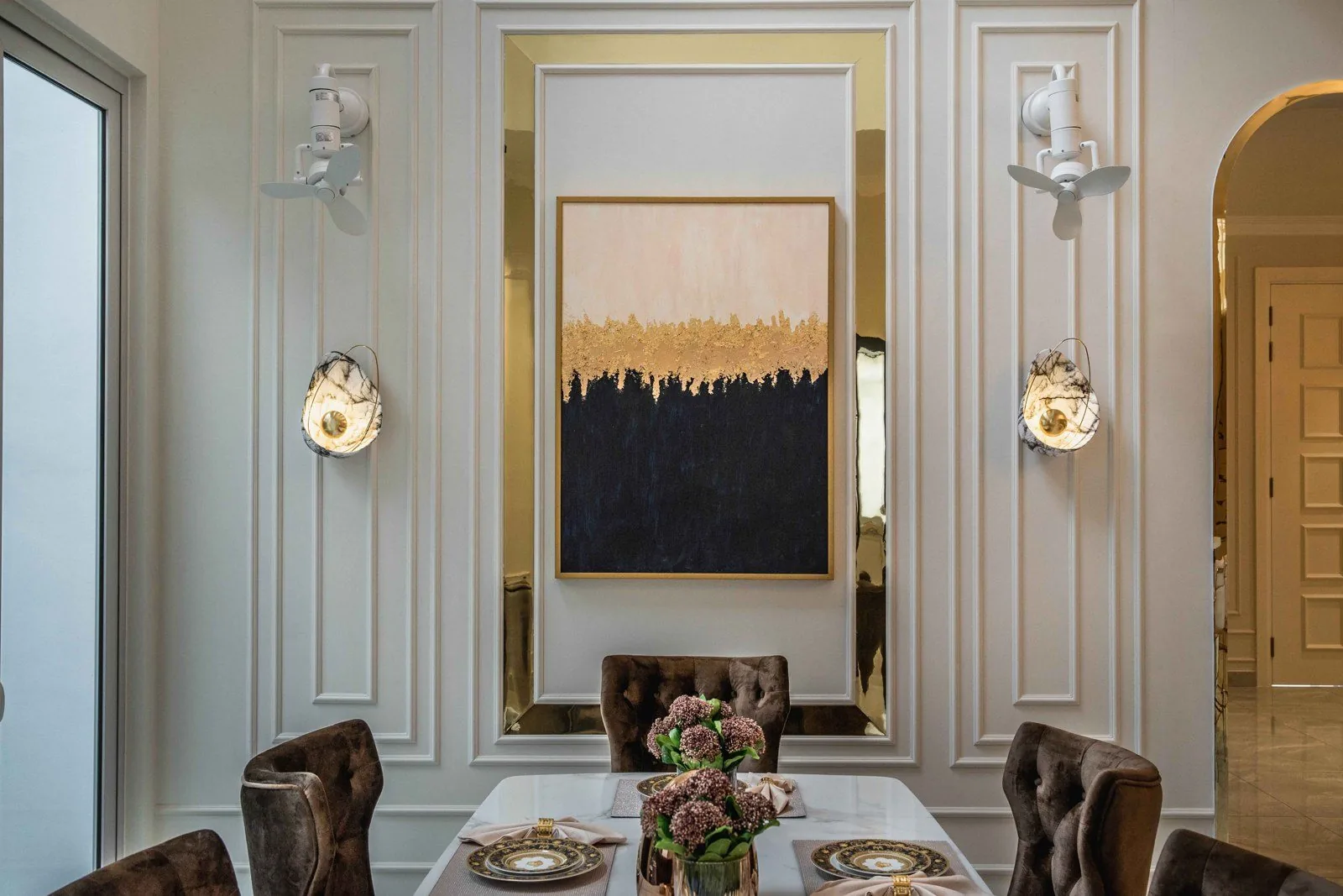 Dining room wainscoting panels with brass-framed art and wall lights at EcoSpring