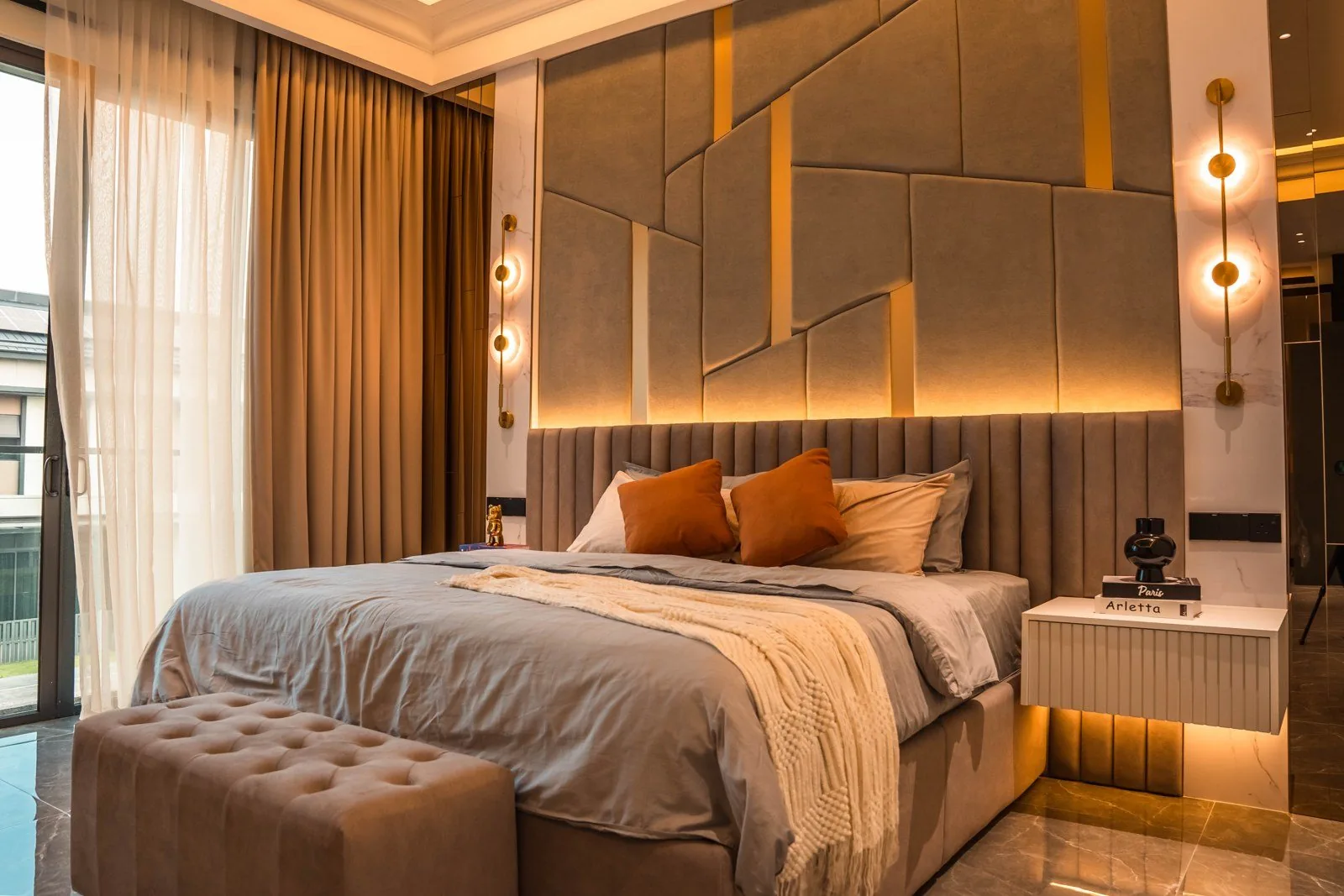 Upholstered overlay panels with brass strips behind a bed at Setia Marina One
