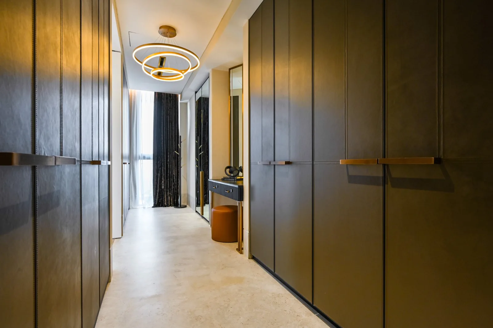 Dark timber-finish hinged wardrobes with long bronze pulls lining the dressing corridor at Aira Residence, Kuala Lumpur