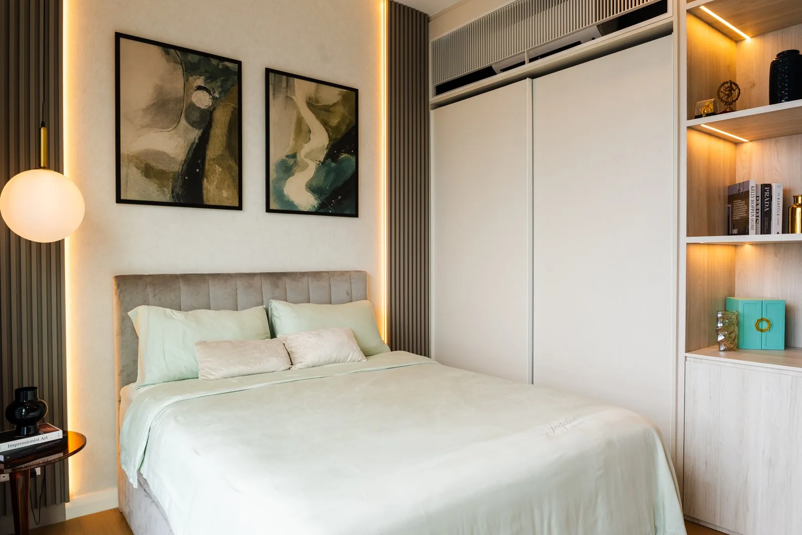 Modern wardrobe with white hinged doors beside a column of lit open shelves in a bedroom at TRX Residence, Kuala Lumpur