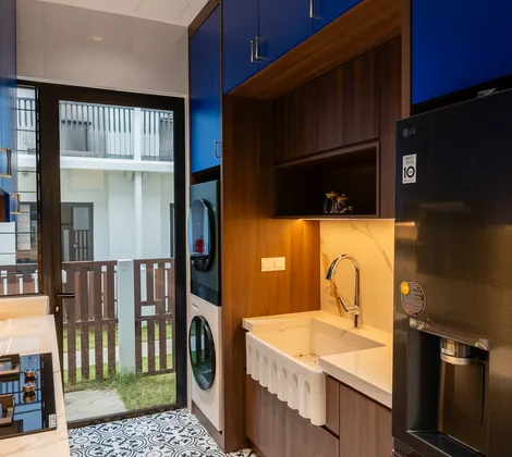 Wet kitchen design in a Cyberjaya landed home: gas hob, deep farmhouse sink, stacked washer-dryer and a back door to the yard