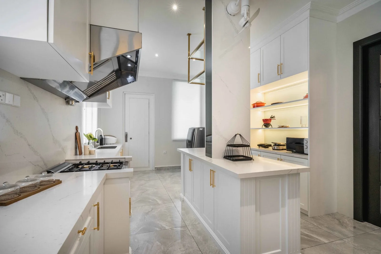 Wet kitchen with a stainless steel chimney hood over a gas hob and white shaker cabinets in an EcoSpring villa