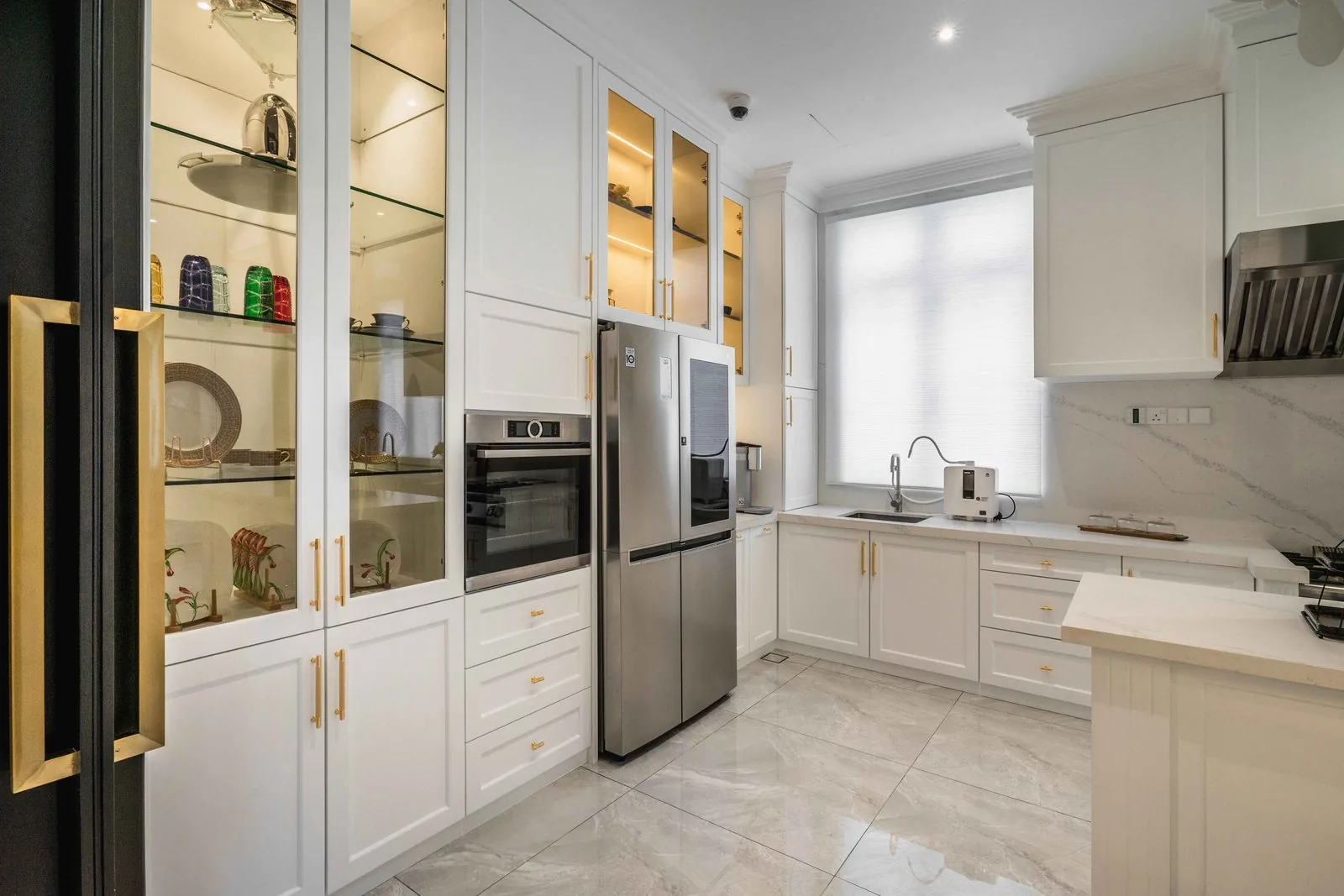 Wet kitchen with glass-front wall cabinets, a stainless steel refrigerator and a sink run in an EcoSpring villa