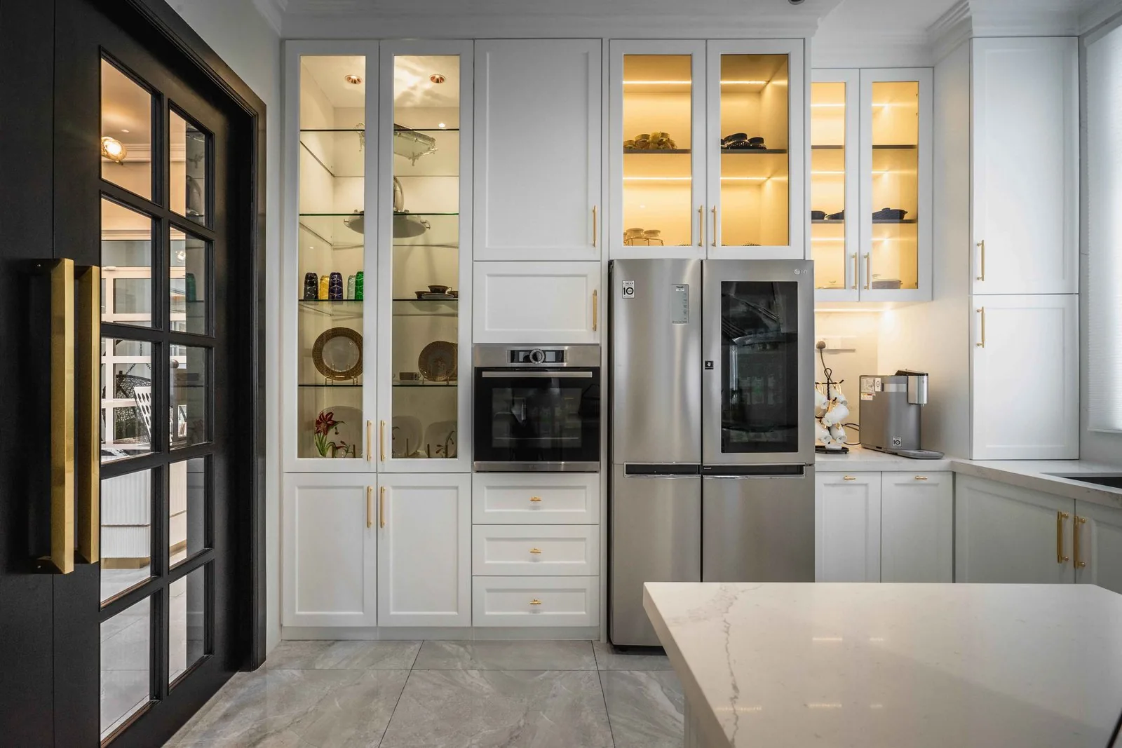 Tall white cabinets with a built-in oven and refrigerator column in an EcoSpring wet kitchen