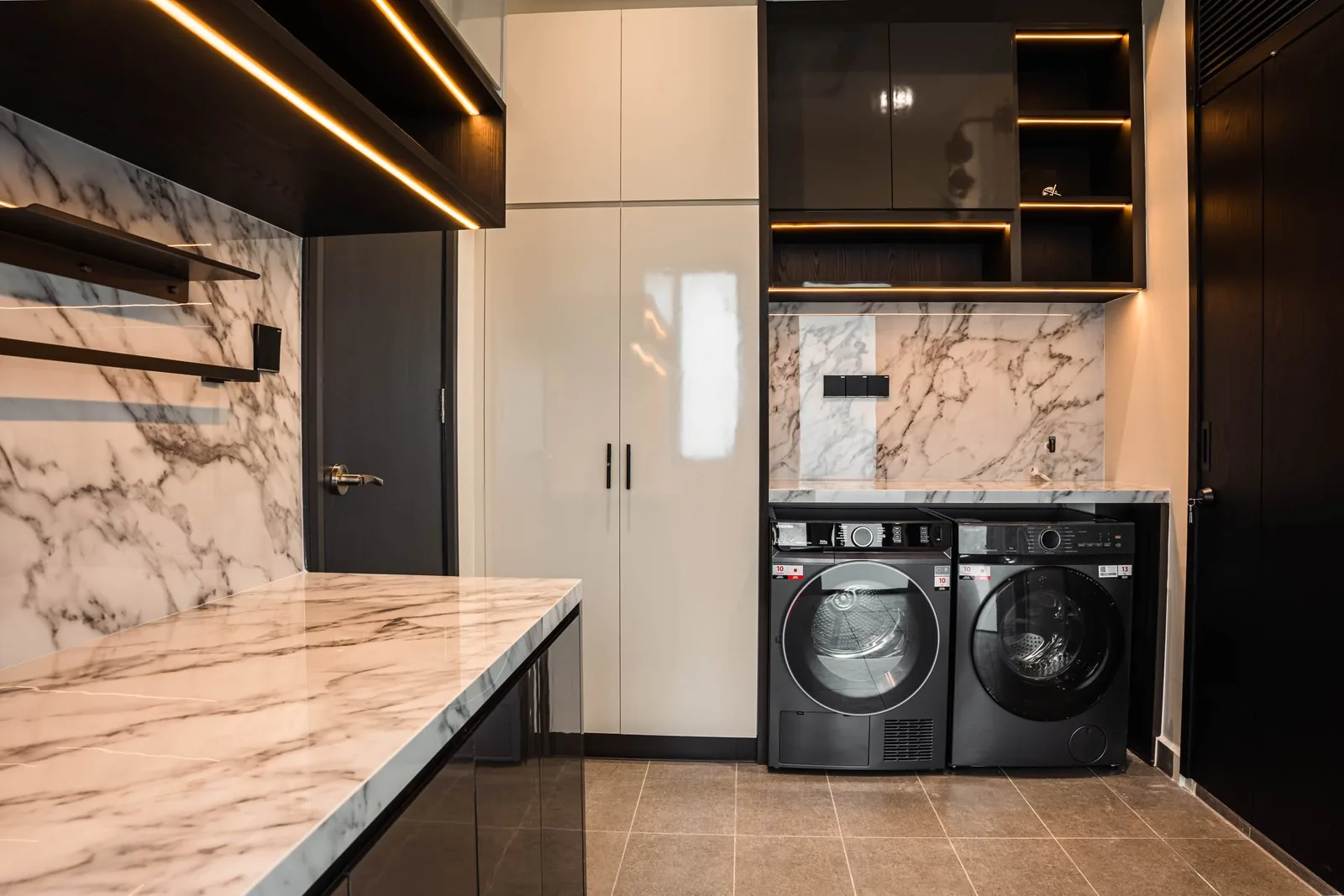 Utility room with a washer and dryer, marble counter and tall cabinets in a Cyberjaya landed home