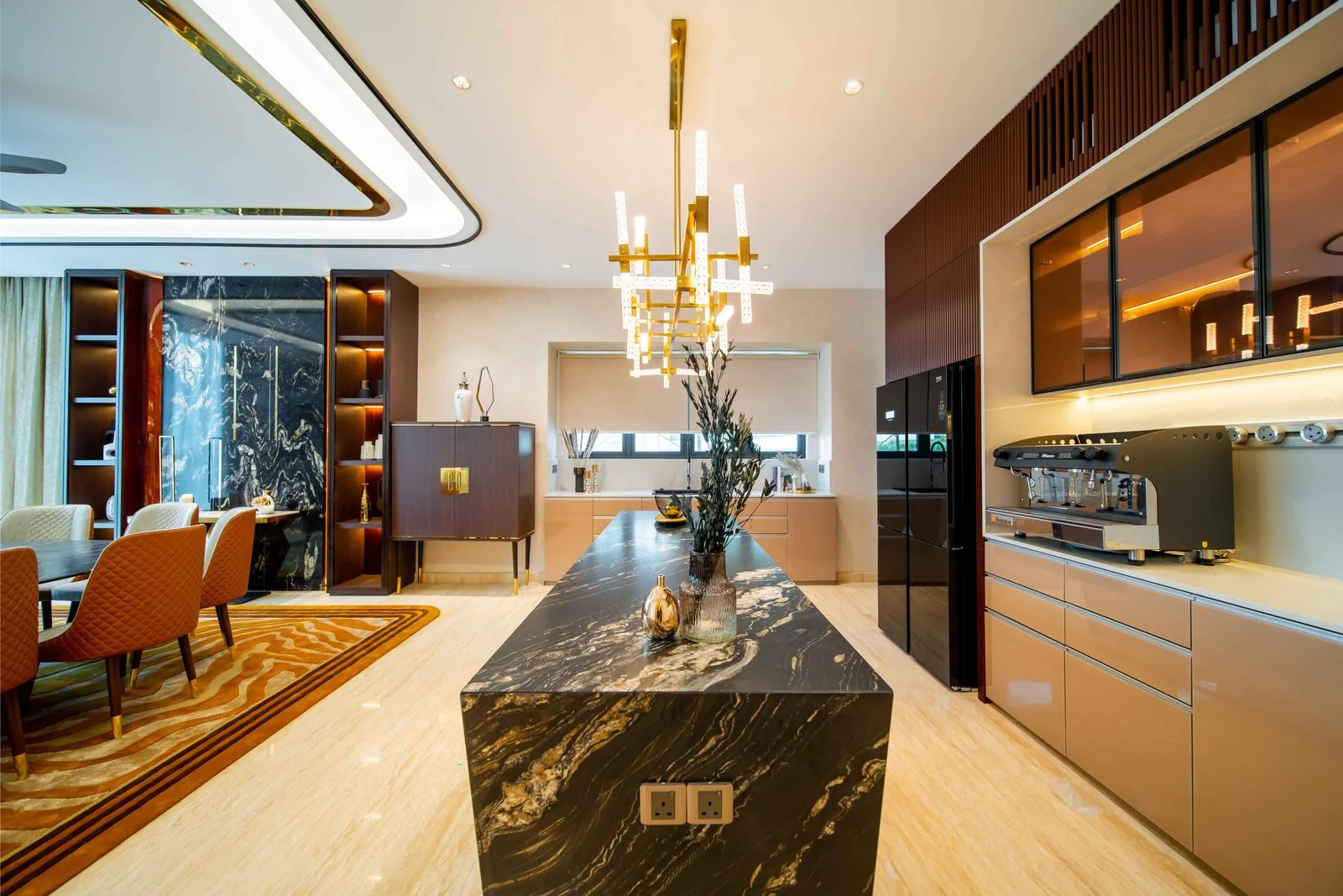 Dry kitchen island in black stone with gold veining under a brass chandelier in a Bangsar bungalow